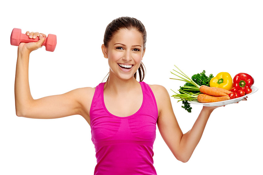 Mujer sosteniendo una bandeja de fruta y verdura mientras hace ejercicio